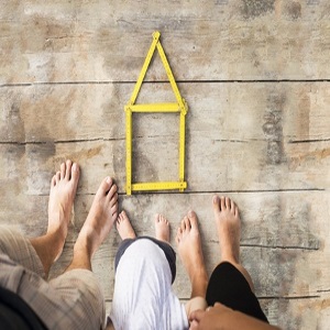 Family of three feet shown by a stick house on a wood deck.