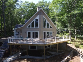 Large deck on house with speciality windows by some woods.